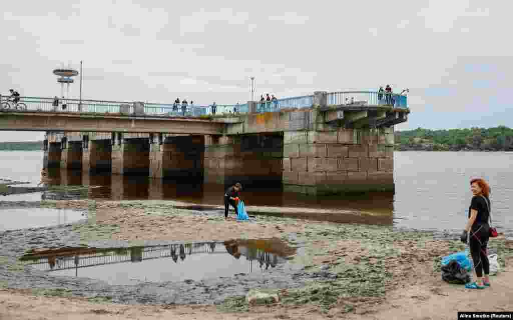 Local residents in&nbsp;Zaporizhzhya clean a city beach on June 10 following the drop in the water level of the Dnieper River. &nbsp;