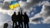 U.K. – Ukrainian personnel hold a Ukrainian flag as they stand on a Challenger 2 tank during training at Bovington Camp, near Wool in southwestern Britain, February 22, 2023