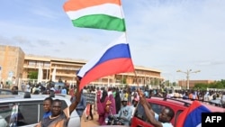 Привърженици на Нигерийския национален съвет за защита на родината развяват нигерийски и руски знамена по време на демонстрация в подкрепа на военния преврат в Ниамей.