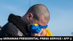 Украинский военнопленный прижимает к лицу национальный флаг после обмена. Украина, 31 января 2024 года