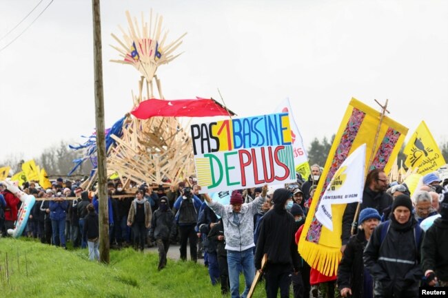 Muškarac nosi plakat dok ljudi marširaju tokom demonstracija koje je sazvao kolektiv "Bassines Non Merci" na gradilištu nove infrastrukture za skladištenje vode za poljoprivredno navodnjavanje u zapadnoj Francuskoj, u blizini Sainte-Soline, Francuska, 25. marta, 2023. Na plakatu piše: "Niti jedan bazen više".