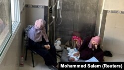 პალესტინელი ქალი ავადმყოფ ბავშვთან ერთად ხან-იუნისის საავადმყოფოში. 24 ივნისი, 2024 წელი 