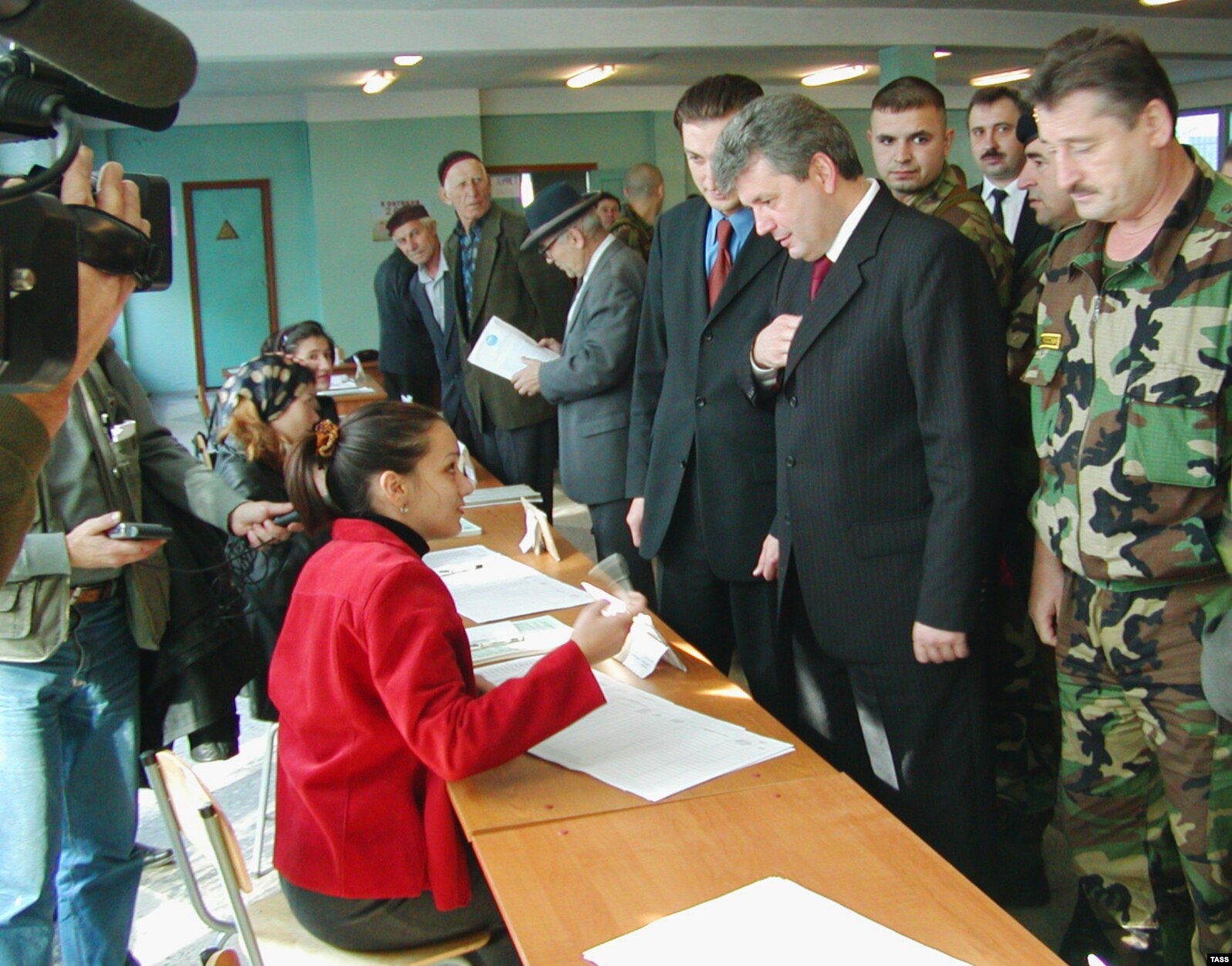 Председатель правительства Чечни Анатолий Попов (второй справа) голосует на участке №347 в Ленинском районе Грозного в окружении охранников, военных и журналистов