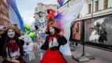Street artists dressed in carnival costumes walk near an installation depicting a Russian soldier as they take part in a procession in Moscow. The theatrical procession took place on June 24, on the eve of an awards ceremony for the National Theater Prize and the Golden Mask festival.