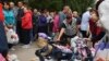 Russians evacuated from fighting during Ukraine's incursion into Russia line up to receive humanitarian aid at a distribution center in Kursk on August 12.