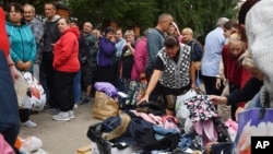 Russians evacuated from fighting during Ukraine's incursion into Russia line up to receive humanitarian aid at a distribution center in Kursk on August 12.