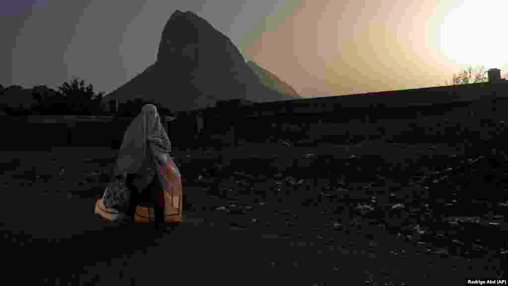 A woman wearing a burqa walks in the early morning on the outskirts of Kandahar City in June. From 2019 to 2020, the poverty rate was nearly 47 percent. Recent data shows that by mid-2022, two-thirds of Afghan households reportedly could not afford food and other basic non-food items, forcing many adults to engage in low-productivity activities to generate income.