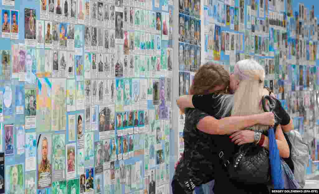 A group of women embrace each other as they react to the Memory Wall commemorating fallen defenders of Ukraine, near St. Michael&#39;s Cathedral in Kyiv.