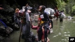 Хора от Хаити преминават през река, докато пресичат прохода Дариен между Колумбия и Панама с надеждата да стигнат до САЩ, 9 май 2023 г. 
