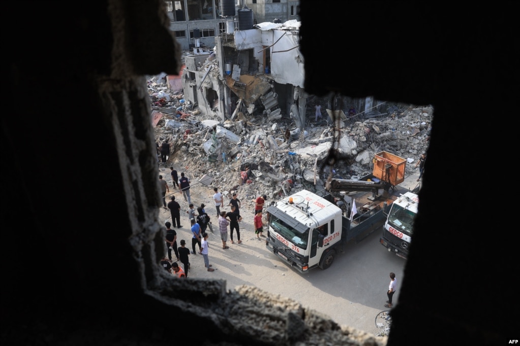 Një kamion pastron rrënojat rreth ndërtesave të shkatërruara nga sulmet ajrore izraelite.