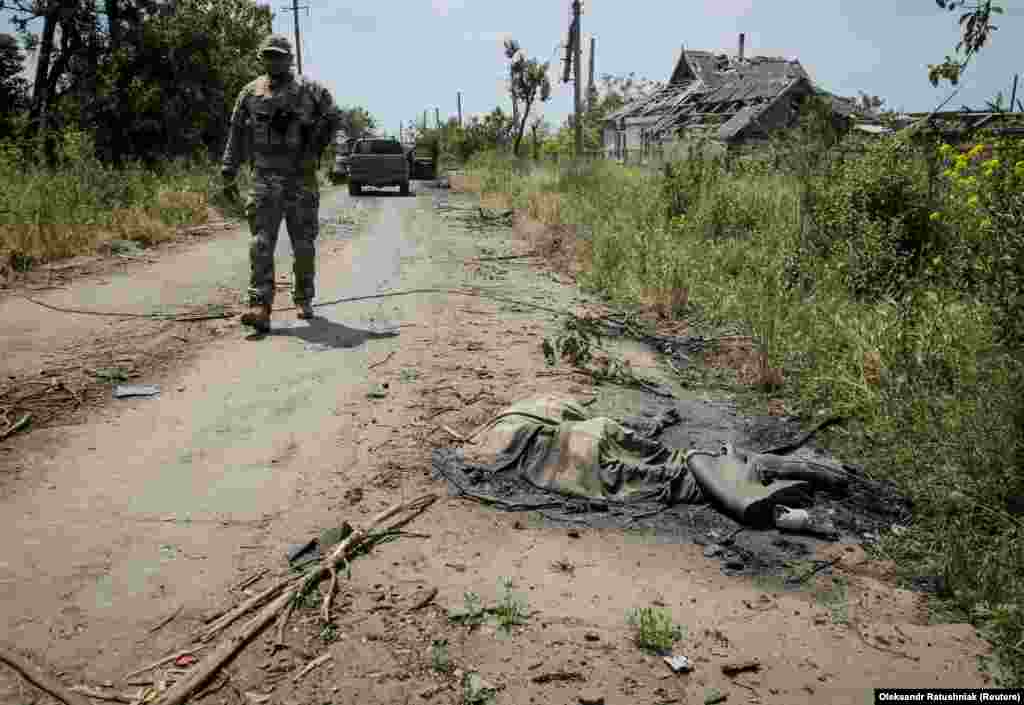 A Ukrainian soldier stands near the body of another Russian soldier.&nbsp;Reuters saw at least three dead Russian soldiers lying in the street.