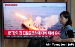Жінка на вокзалі в Сеулі проходить повз екран, на якому показують кадри запуску ракет Північною Кореєю. 2 вересня 2023 року