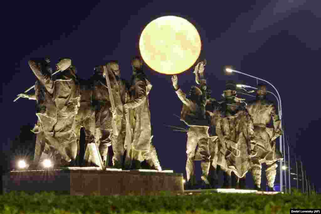 A super moon rises behind a Soviet-era monument for defenders of Leningrad, now St. Petersburg, in World War II, in St. Petersburg.