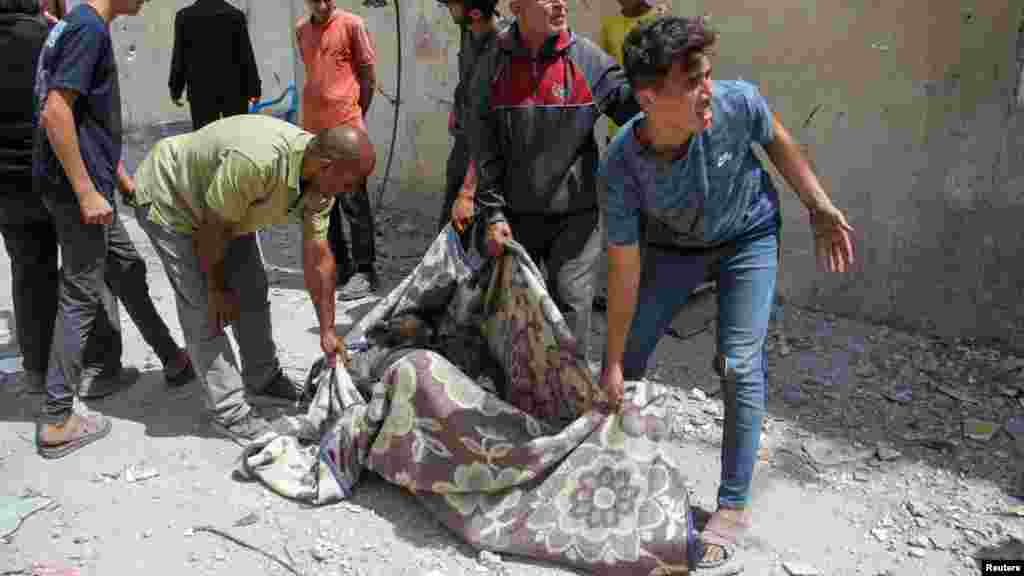 A palesztinok egy férfi holttestét viszik Zeitúnban 2024. május 15-én, az izraeli hadsereg rajtaütését követően.&nbsp;A hadsereg a támadások megkezdése előtt elrendelte, hogy a civileket saját biztonságuk érdekében evakuálják