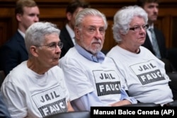 Grupa ljudi u publici tokom saslušanja s majicama na kojima piše "Uhapsite Faučija".