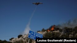 Kanader ispušta vodu dok vatrogasci pokušavaju da ugase požar u blizini grada Koropi, Grčka, 19. jun 2024. REUTERS/Louisa Gouliamaki