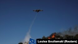 Канадер испушта вода додека пожарникарите се обидуваат да изгаснат пожар во близина на градот Коропи, Грција, 19 јуни 2024 година. 