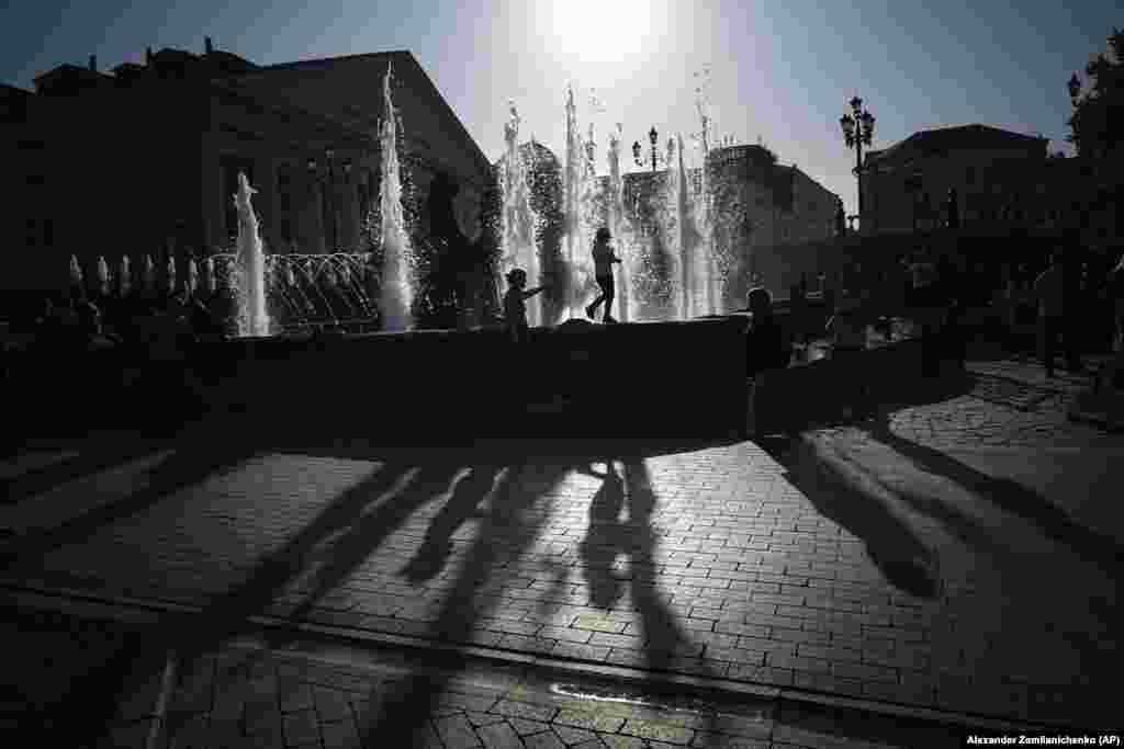 Children play at a fountain during sunset near the Kremlin Wall in Moscow.