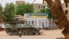 سربازان ارتش سودان در نزدیکی یک پست ایست بازرسی زیر سایه یک تانک در حال استراحت هستند