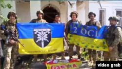 Ukrainian forces hold up flags in celebration of liberating the village of Pyatykhatky in the Zaporizhzhya region on June 19.