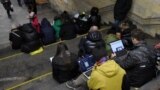 Ljudi provjeravaju informacije na svojim uređajima na stanici podzemne željeznice u Kijevu tokom vazdušnog napada u martu 2023. 