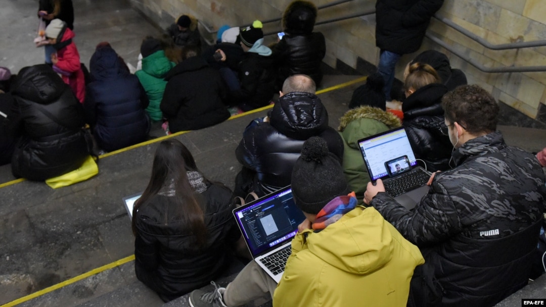 People check their devices for information in a Kyiv subway station during an air raid in March 2023.
