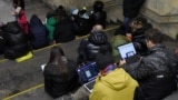 People check their devices for information in a Kyiv subway station during an air raid in March 2023.