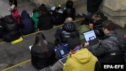 People check their devices for information in a Kyiv subway station during an air raid in March 2023.
