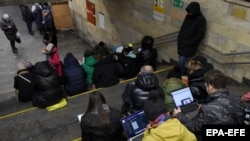 Njerëzit duke i shikuar pajisjet e tyre për të dhëna në një metro në Kiev gjatë një paralajmërimi për sulme ajrore, mars 2023.