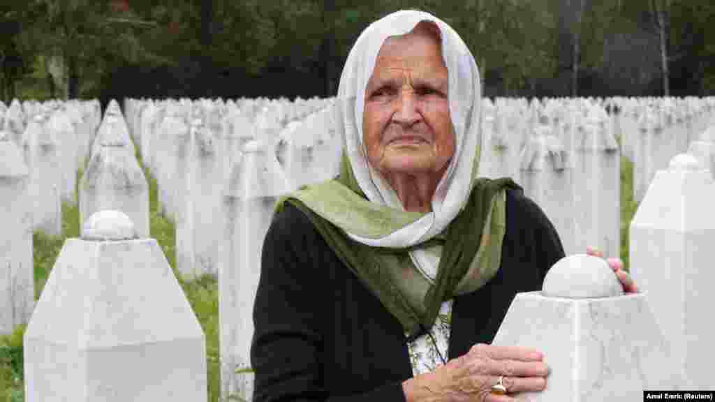 Žena dodiruje nadgrobni spomenik na memorijalnom groblju u Srebrenici, Bosna i Hercegovina.