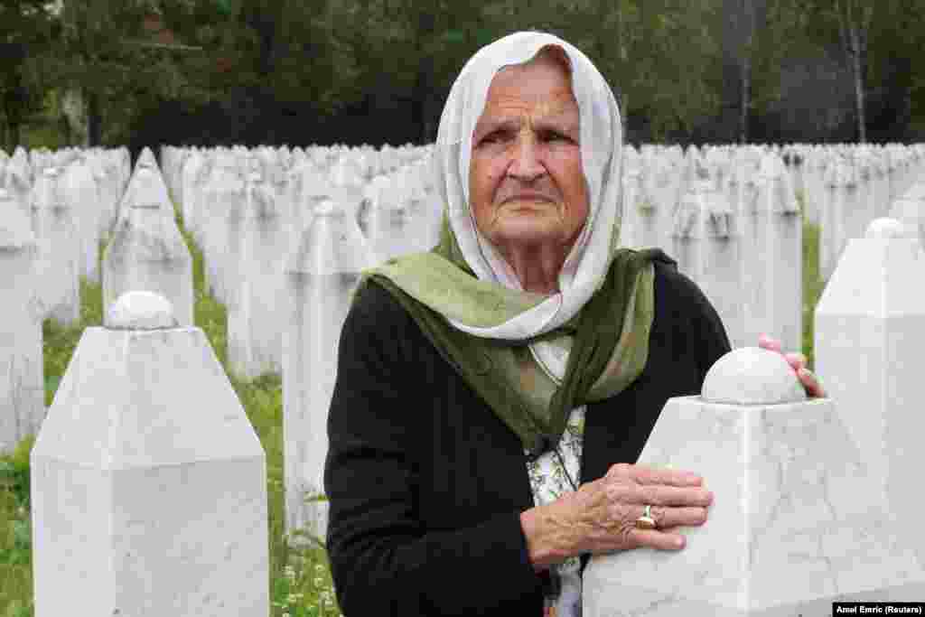 A woman touches a gravestone at the memorial cemetery in Srebrenica, Bosnia-Herzegovina.
