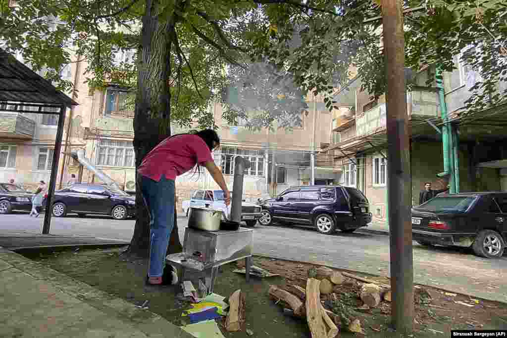 A woman cooks on a makeshift outdoor stove near a street in Stepanakert. Stepanian has said that at least 200 people were killed and about twice as many wounded during the latest fighting, including children.