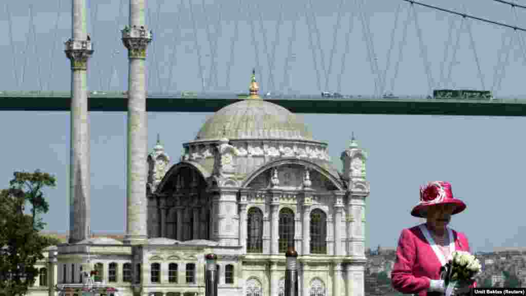 Королева Елизавета позирует на борту лодки на фоне мечети Ортакёй и Босфорского моста во время своего государственного визита в мае 2008 года. Тогда она посетила Турцию, чтобы укрепить дипломатические отношения Соединенного Королевства и Турецкой Республики, а также отдать дань уважения османскому наследию страны