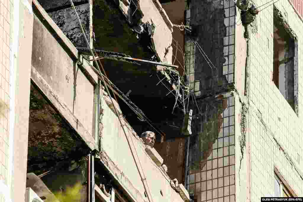 A man looks from the window of a burned flat in Vuhledar town, Donetsk region, July 16, 2023.