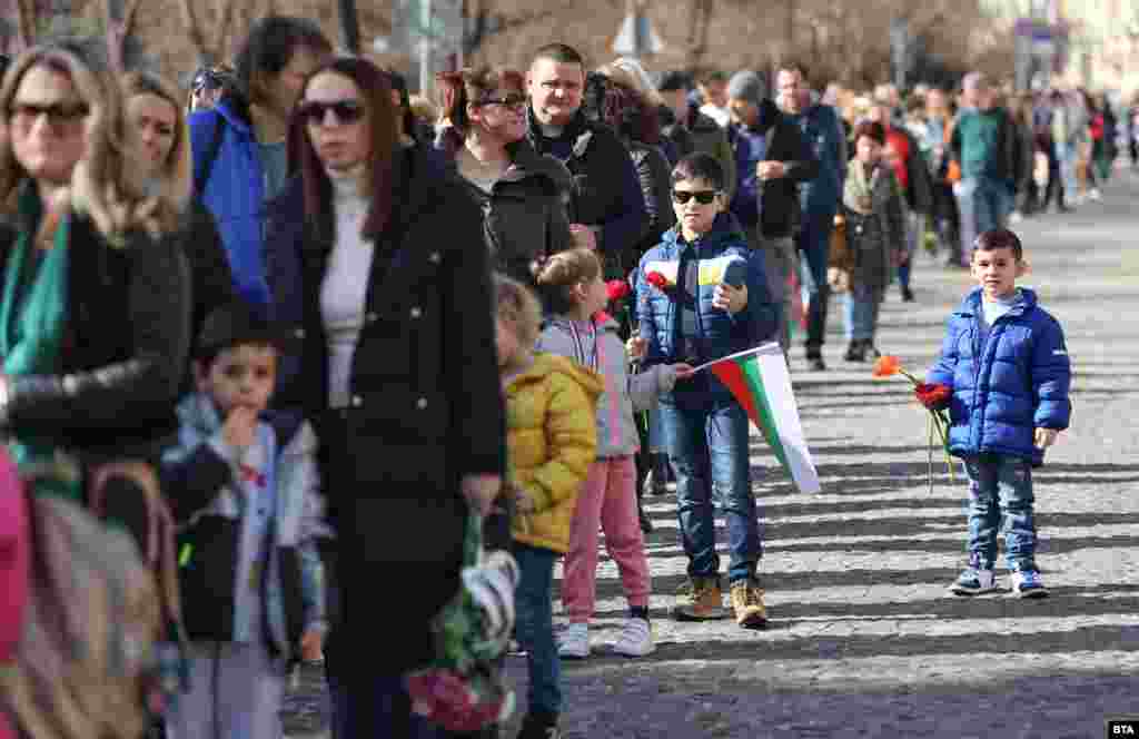 Десетки семейства се събраха в центъра на София в слънчевия 19-ти февруари. Децата държаха по цвете или българското знаме, докато изчакваха реда си да стигнат до паметника на Васил Левски.&nbsp;
