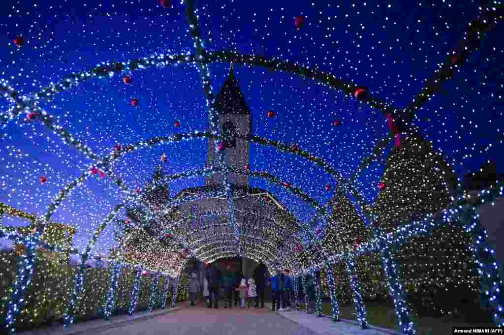 People walk under Christmas decorations at the local Catholic church in the village of Petrushan, near the town of Gjakova in Kosovo.&nbsp;