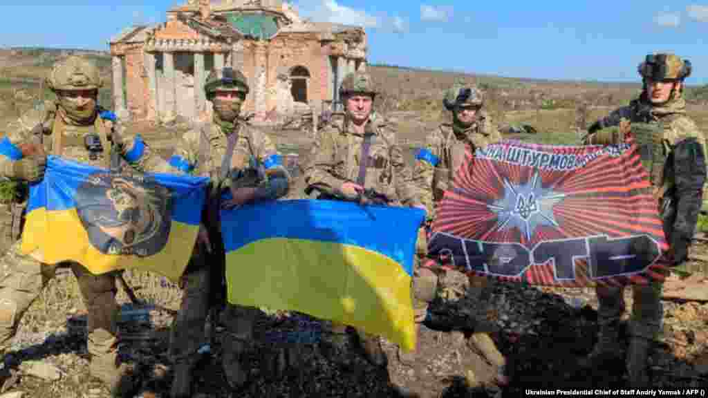 A Kijev által kiadott fényképen ukrán katonák pózolnak ukrán nemzeti zászlókkal egy lerombolt épület előtt Kliscsijivka faluban szeptember 17-én. Zelenszkij elnök bejelentette, hogy az ukrán csapatok felszabadították a Bahmut déli részén fekvő Kliscsijivka települést. A bejelentés két nappal azután történt, hogy az ukrán hadsereg közölte, hogy ellenőrzésük alá vontak egy közeli kis falut, Andrijivkát, mintegy tíz kilométerre délnyugatra Bahmuttól