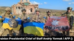 This photograph released by Ukrainian presidential chief of staff Andriy Yermak shows Ukrainian soldiers posing in front of a destroyed building in the village of Klishchiyivka on September 17.