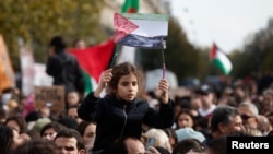  Момиче държи афиш с изрисувано палестинско знаме в Париж в неделя. 