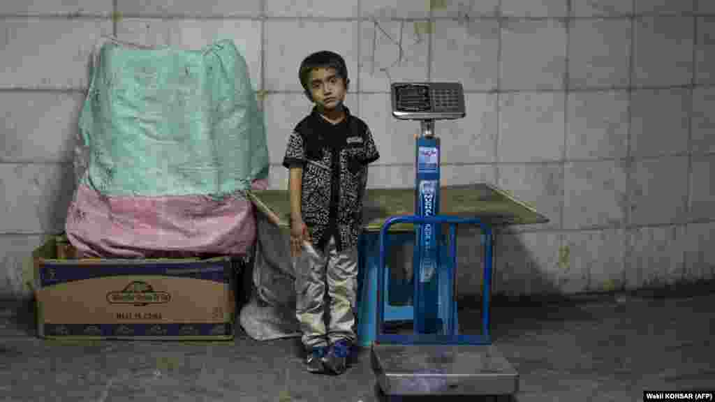 An Afghan boy stands besides a scale while waiting for customers at an underground passageway in Kabul on June 27. Traders in Afghanistan are struggling with sales as the three-day&nbsp;Muslim festival Eid al-Adha, or Festival of Sacrifice, begins on June 28.&nbsp;