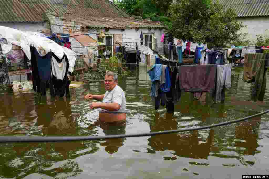A man walks in the flooded yard of his house in Afanasiyivka in Ukraine&#39;s Mykolayiv region.