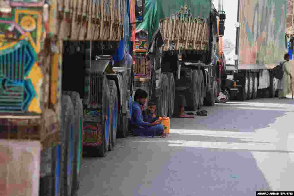 Drivers sit beside their trucks carrying goods destined for Afghanistan as they wait for the opening of the border following clashes between security forces of Pakistan and Afghanistan, in Torkham, Pakistan, on September 7.