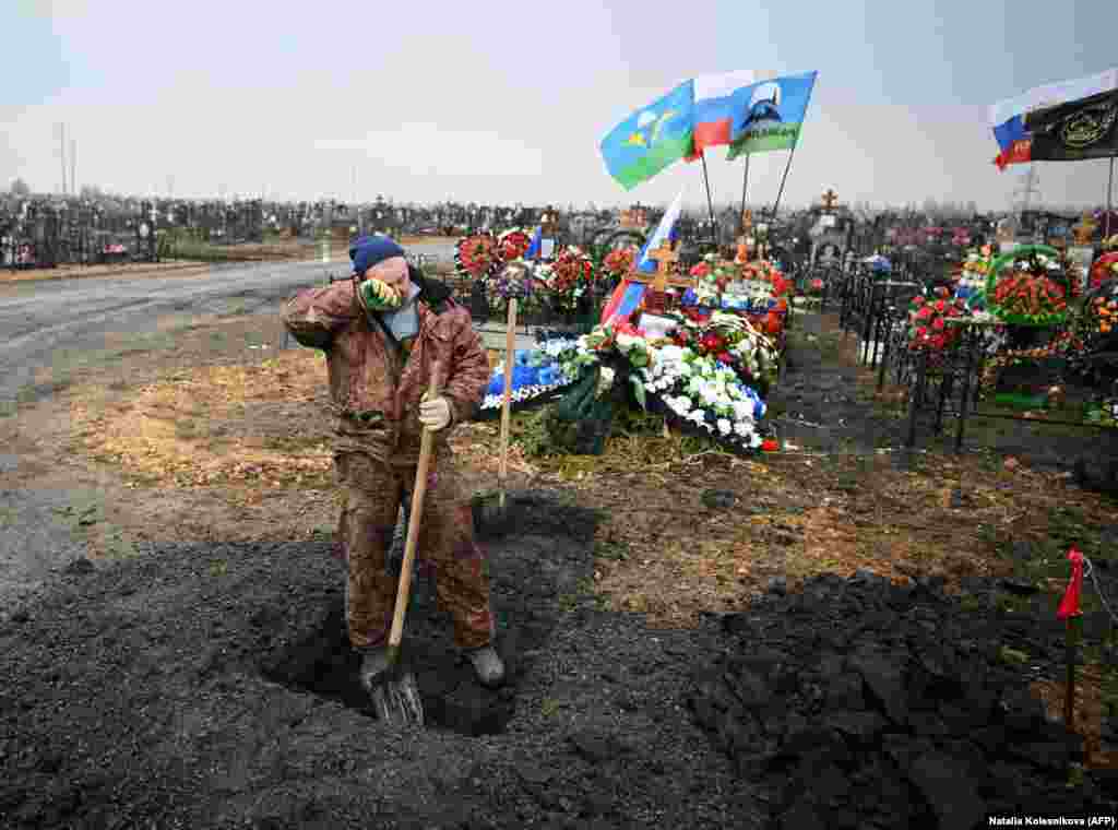 Një varrmihës pushon gjatë punës së tij pranë varreve të ushtarëve rusë në Yefremov, në rajonin Tula në Rusi, në mars 2023. &nbsp;