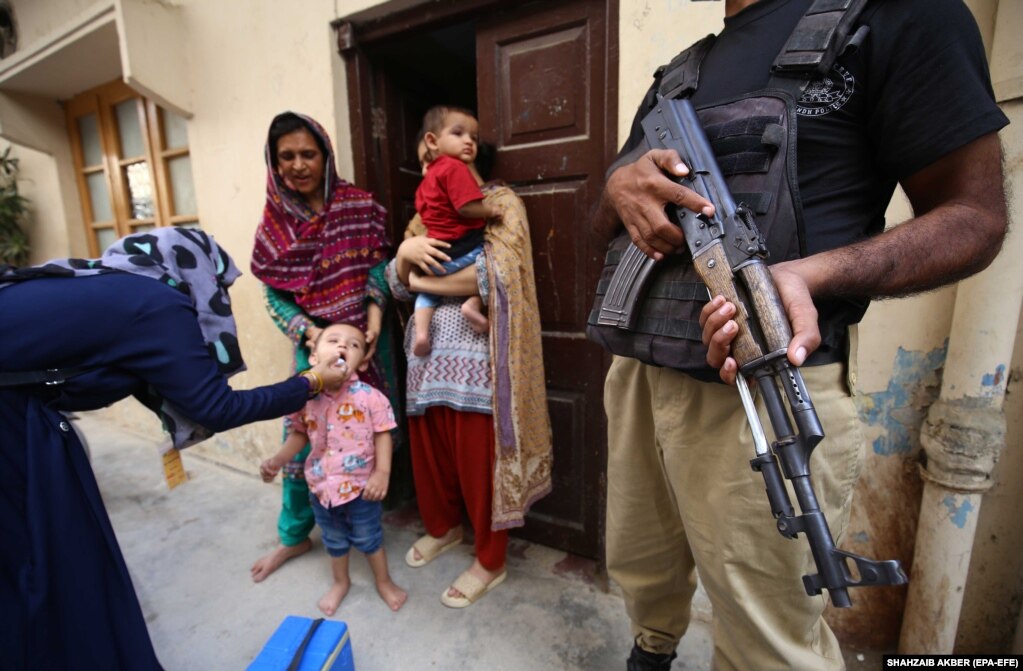 Policia shoqëron punonjësit e shëndetësisë teksa i vaksinojnë fëmijët kundër poliomielitit Karaçi, Pakistan.