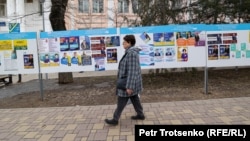 Депутаттыққа кандидаттардың үгіт парақтары ілінген маңнан өтіп бара жатқан адам. Алматы, 3 наурыз, 2023 жыл.