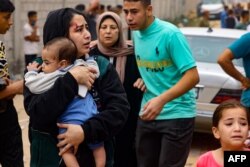 Povrijeđena žena nosi bebu nakon izraelskog bombardovanja u Rafi na jugu Pojasa Gaze, 29. oktobra