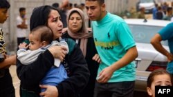 O mamă îşi poartă copilul în braţe, după un bombardament al armatei israeliene în oraşul Raffah, din sudul Fâşiei Gaza, la graniţa cu Egiptul.