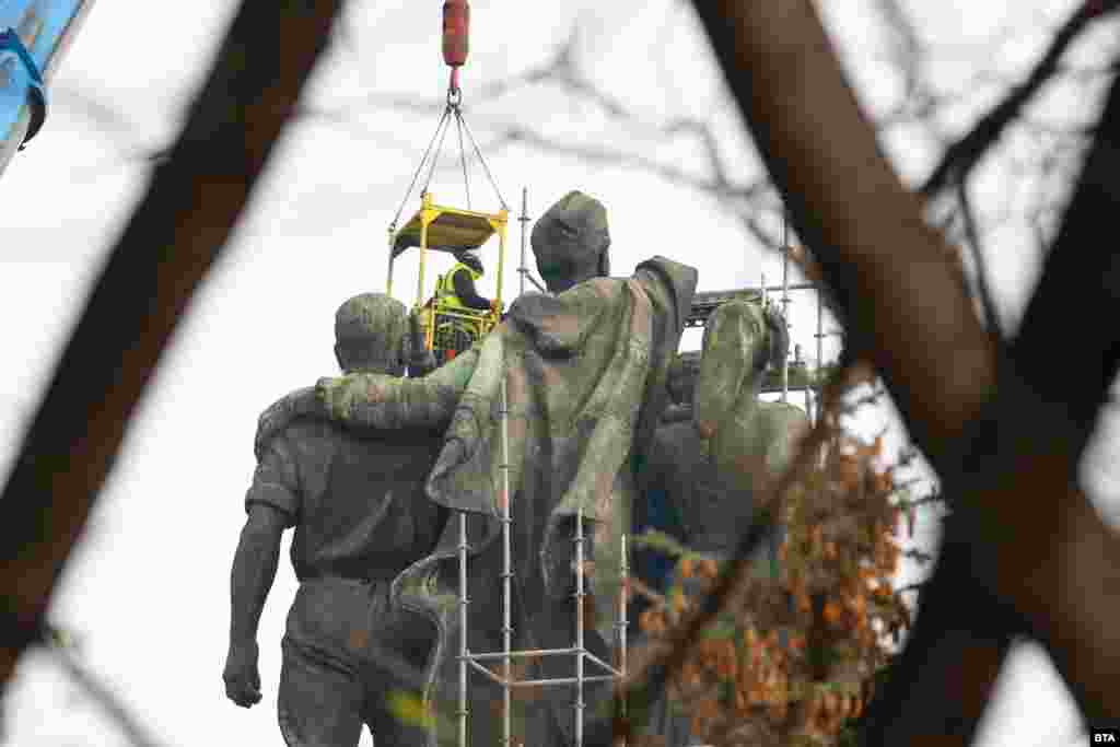 Two workers suspended above the lead figures of the partially dismantled Monument To The Soviet Army on the morning of December 13. The topmost portion of the monument -- depicting a Soviet soldier&rsquo;s outstretched right arm and submachine gun -- was cut off the night before. &nbsp;
