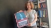 Investigative journalist Nino Zuriashvili with a photo of her face and the caption "There is no place in Georgia for agents."