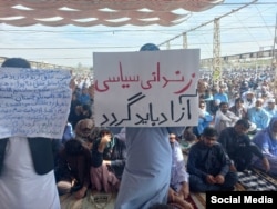 A protester in Zahedan holds a placard that reads: "Political prisoners must be released."